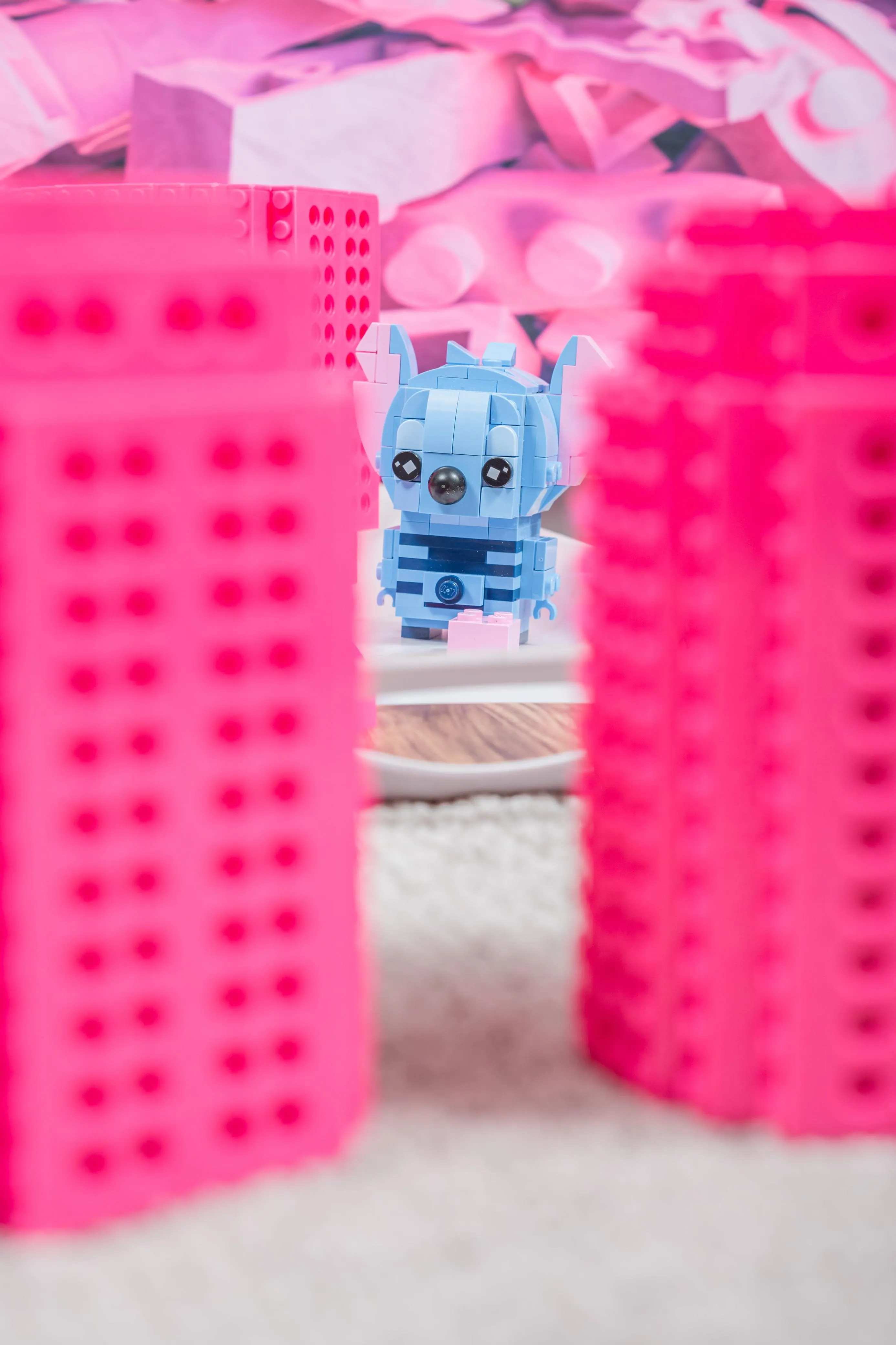 A small toy figure sits between colourful brick props in a brick-patterned setup.