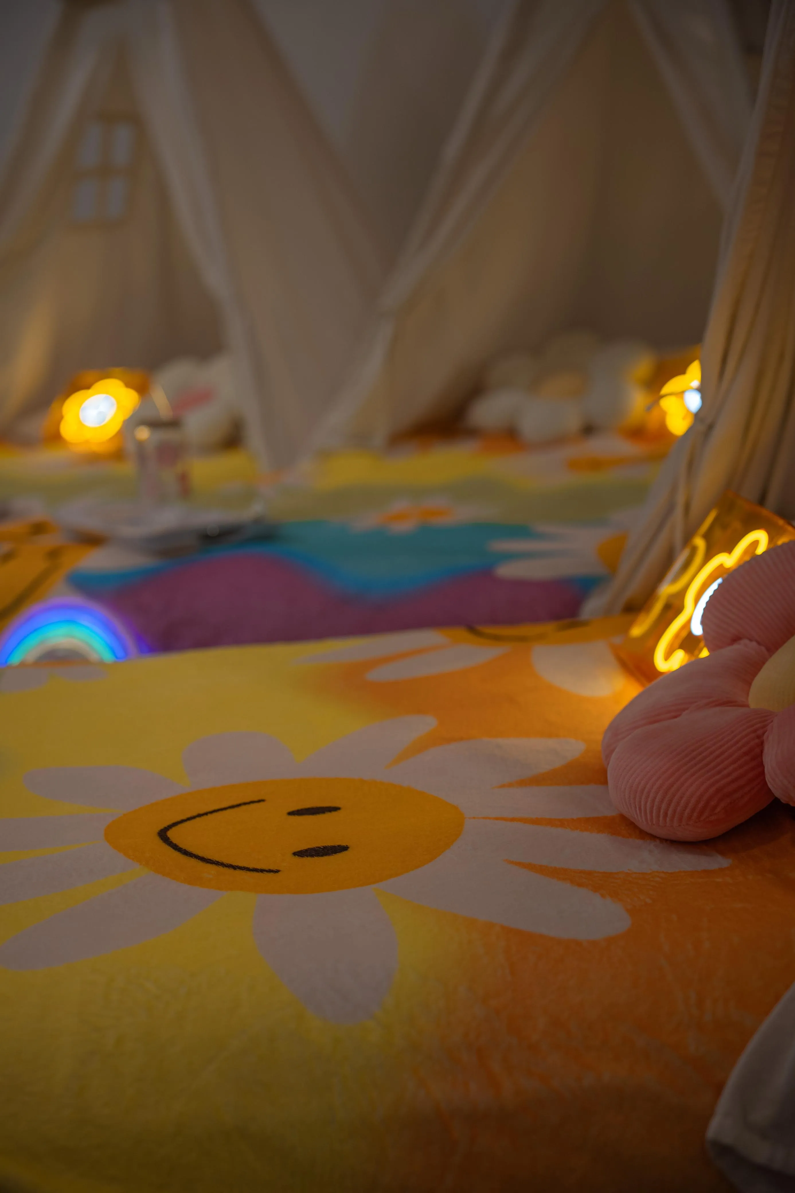 A glowing flower lamp beside flower-pattern bedding and a rainbow light.