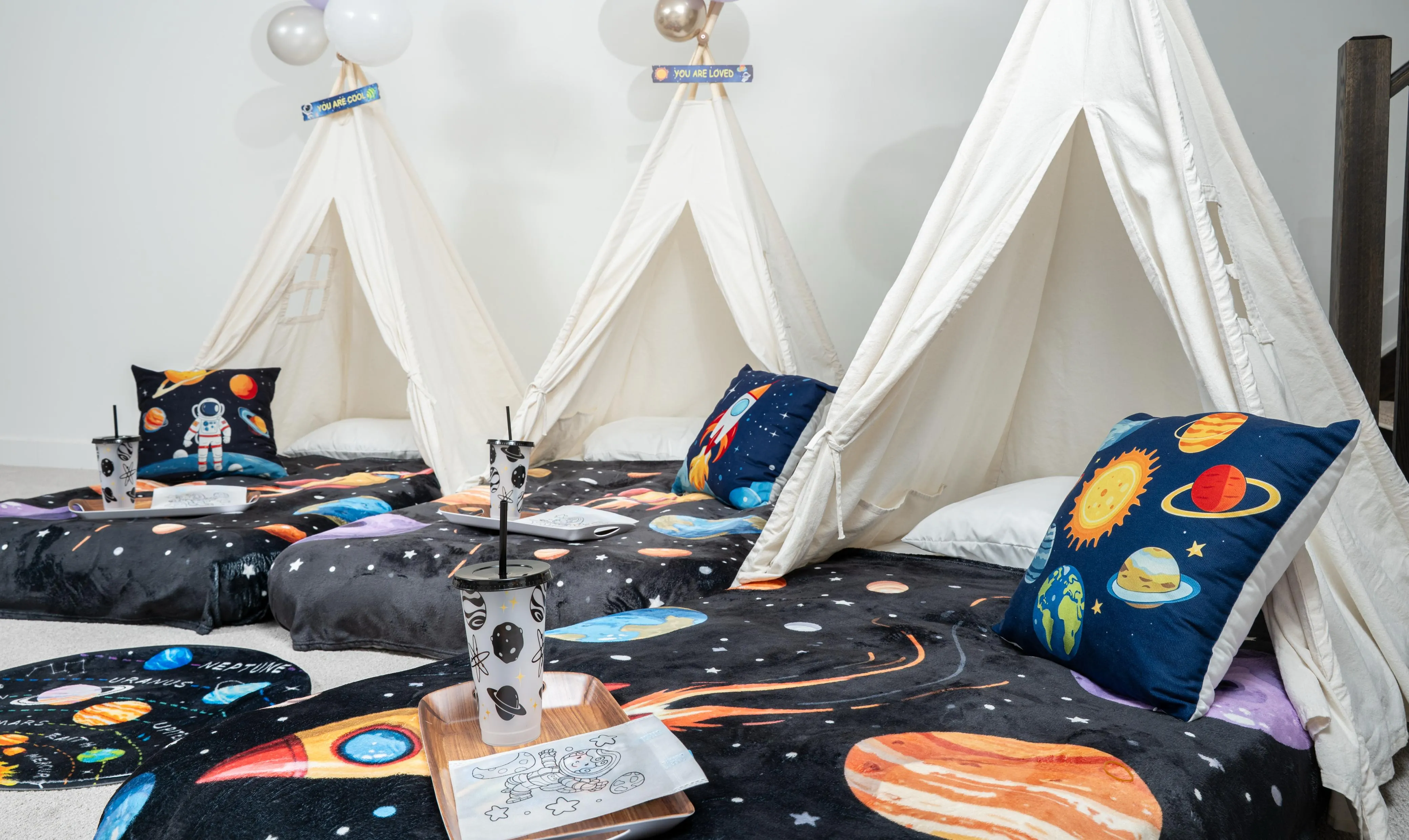 Three cream sleepover tents with space-themed bedding and trays.
